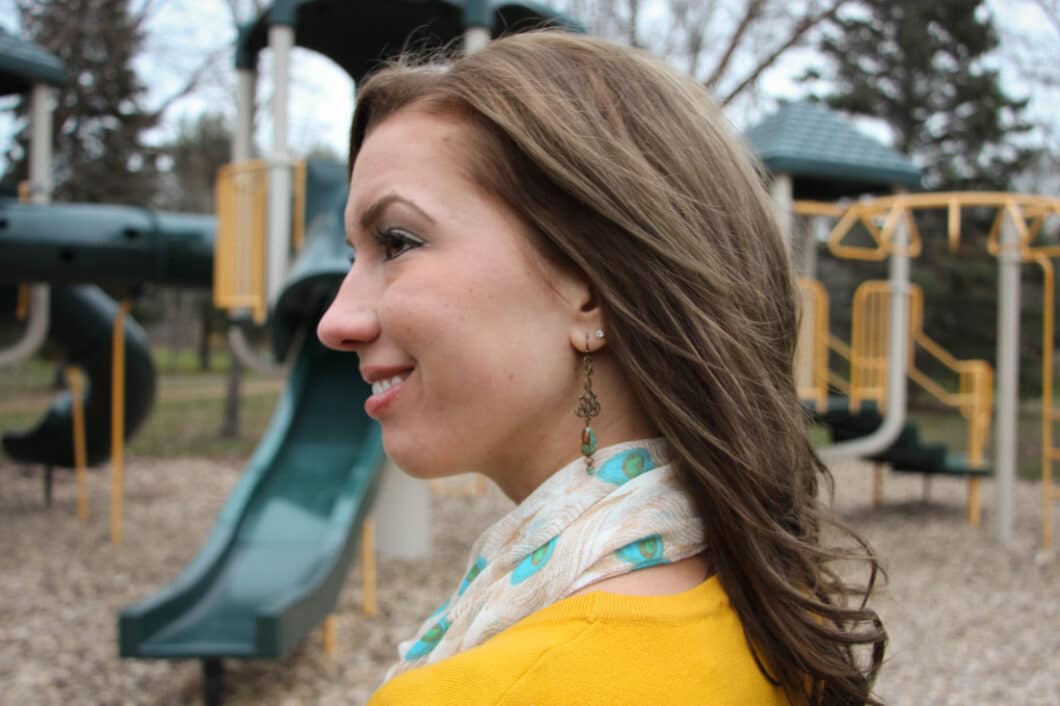 A profile shot of Lindsey from Have Clothes, Will Travel. She's wearing a yellow sweater and scarf and her hair is blowing in the wind.