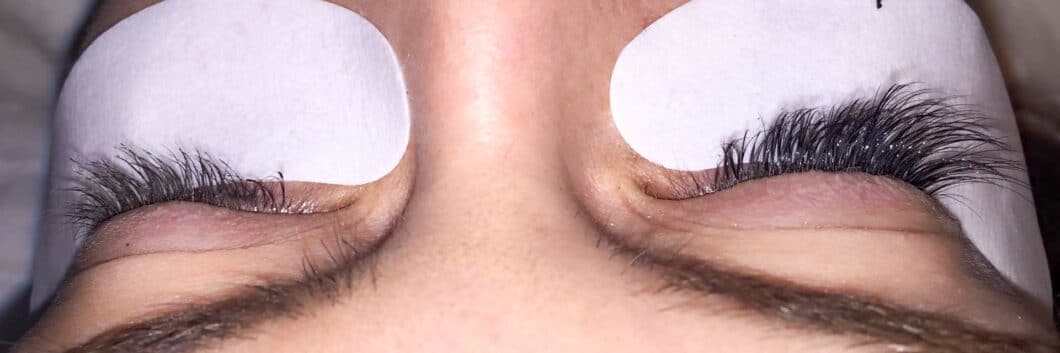 A closeup image of a woman's eyes during an eyelash extension procedure. Her left eye has short lashes with some mascara on them, while her right eye has longer, fuller lashes thanks to Novalash eyelash extensions.