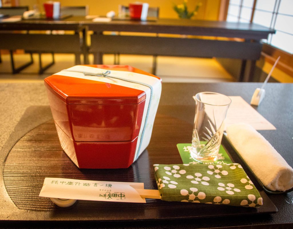 The dinner presentation during an evening with Geishas included a stylish red bowl, green floral napkin, chopsticks, and glassware.