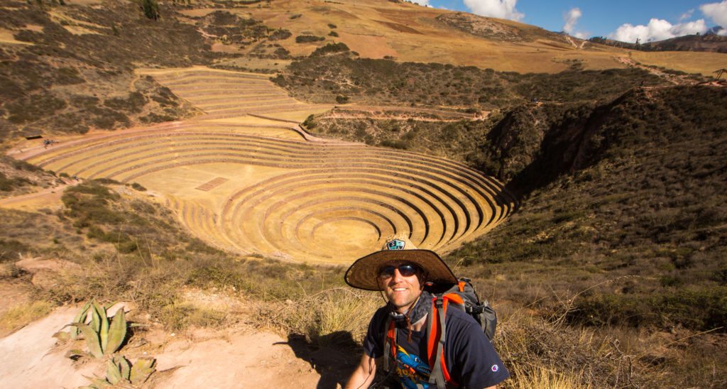 A man in a hat is standing in front of a circular structure.