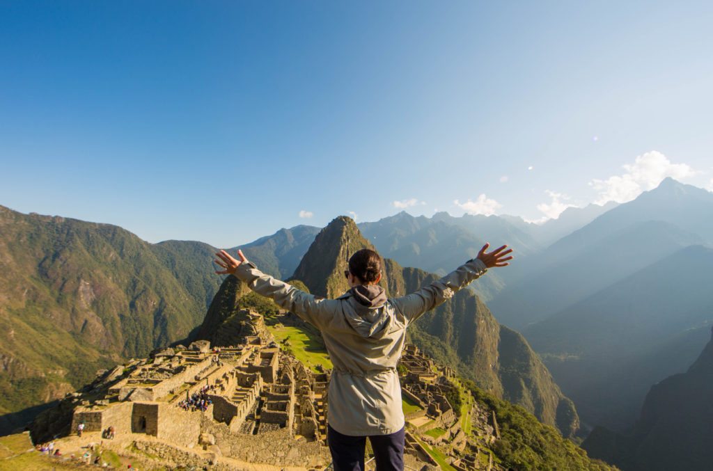 Woman standing on top of machu picchu with arms outstretched.