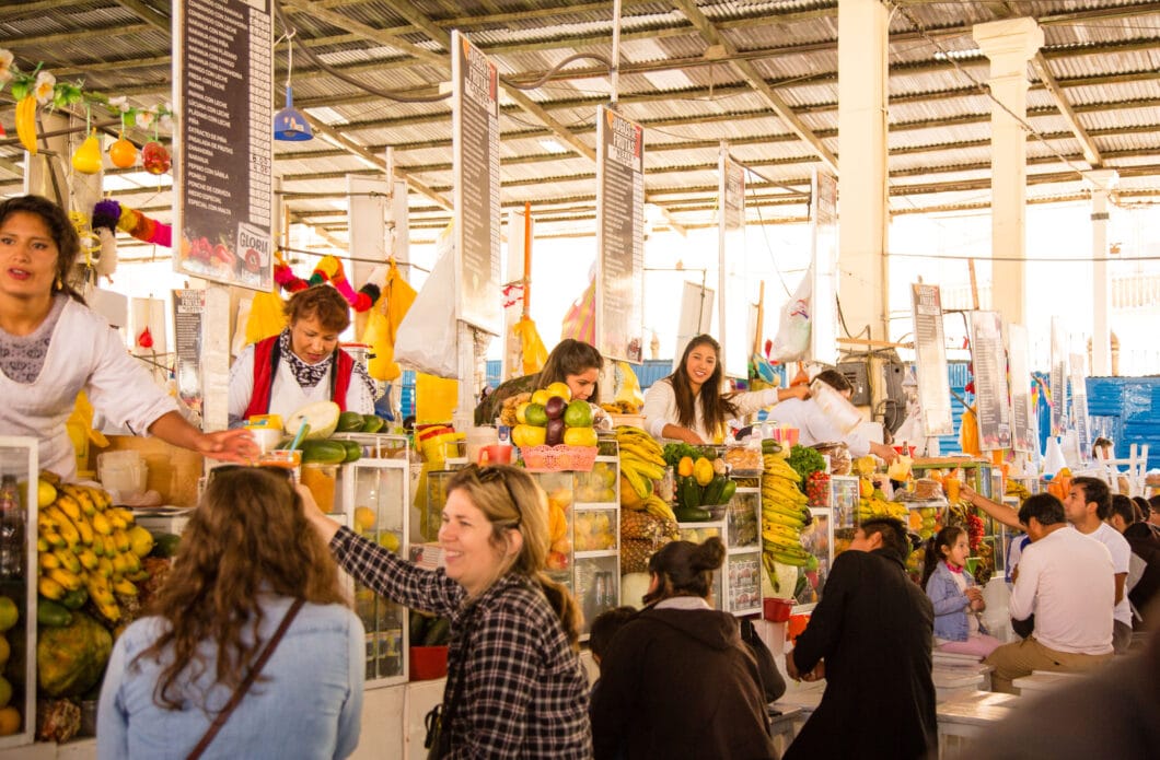 A group of people buying juice at San Pedro Market juice stalls.