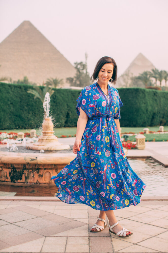 A woman wearing a blue dress in front of the pyramids at Mena House Cairo.