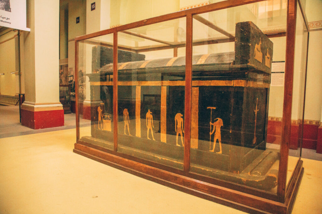 The sarcophagus of an Egyptian noble named Tuya. The sarcophagus is black with gold inlays of Egyptian figures, displayed in a glass case.