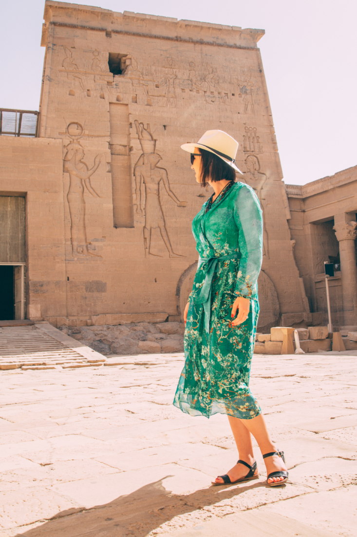 Lindsey of Have Clothes, WIll Travel wearing a fedora and a green maxi dress in front of the Philae Temple in Egypt.