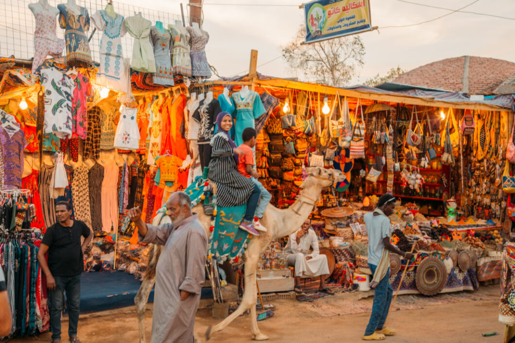 A local Nubian woman rides a camel along the vendor-lined streets of the Nubian village.