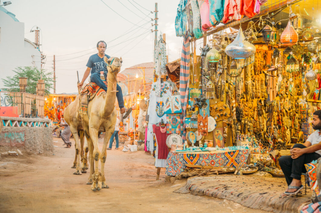 Man riding a camel in colorful Nubian Village in Aswan, Egypt