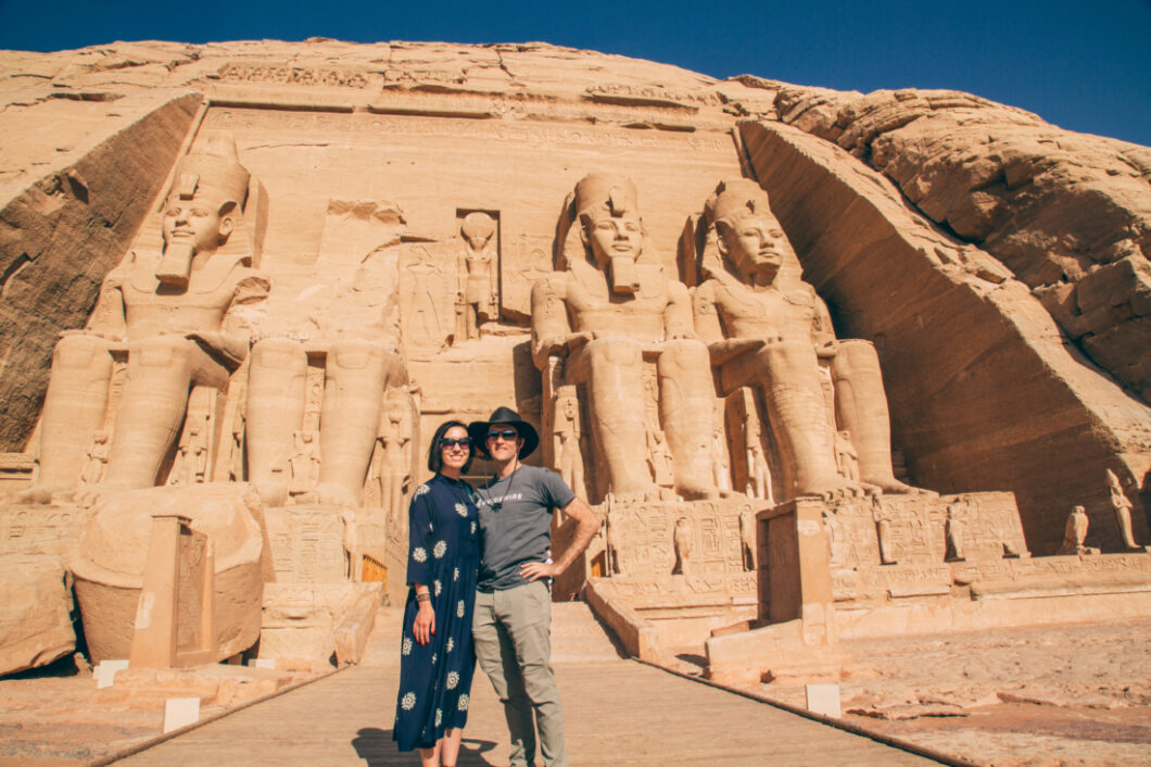 A couple smiling and posing in front of Nefertari's temple at Abu Simbel, Egypt.