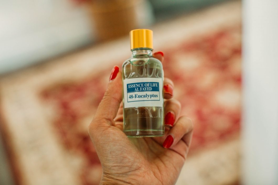 A woman with red nail color holding a bottle of Eucalyptus essential oil in her hand. 