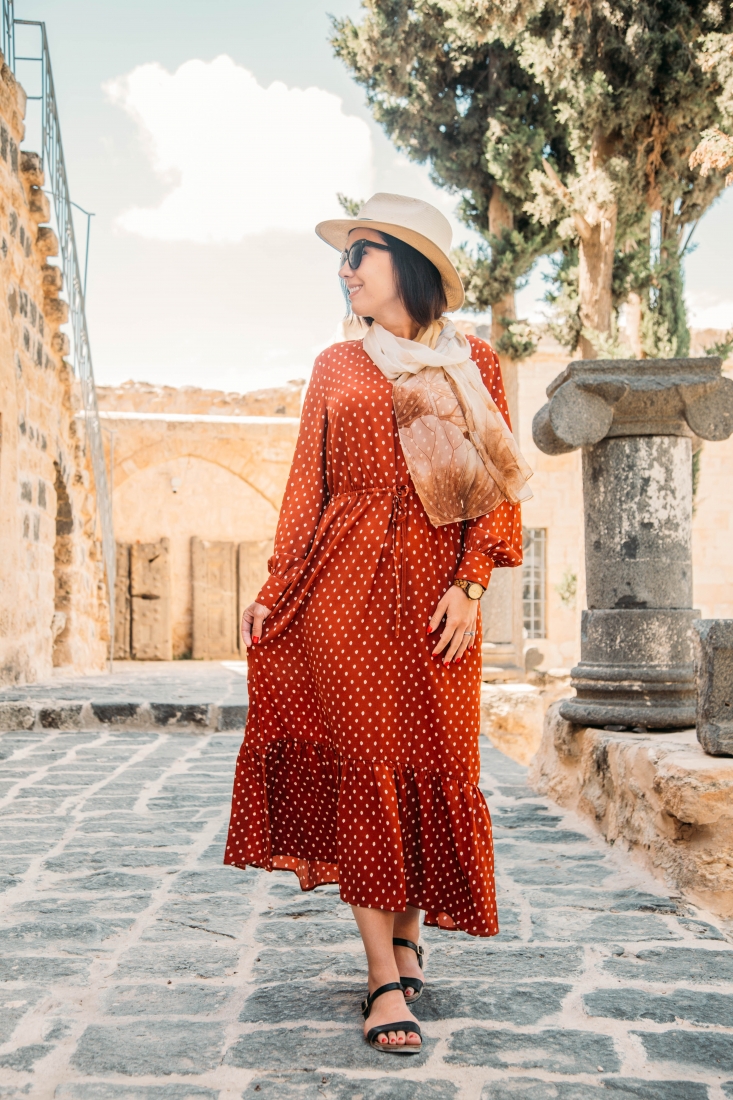 A woman wearing an orange polka dot dress and hat in Jordan.