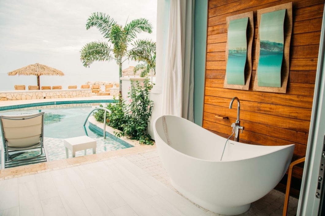 A soaking tub outside a room at the resort on the ground floor with a swim up pool next to it