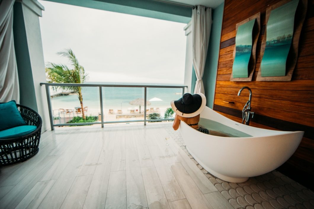 A woman sits in a luxurious bathtub that overlooks the waterfront vistas at Sandals Resort in Montego Bay, Jamaica.