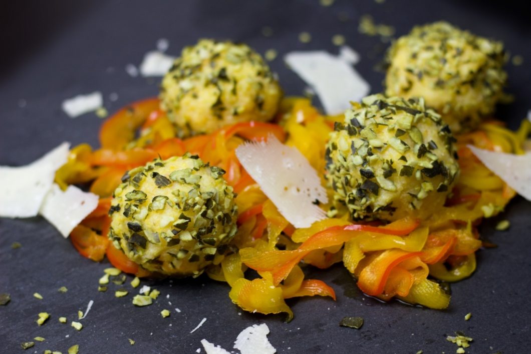 A plate of vegetable noodles topped with shaved Parmesan cheese and Polenta balls.