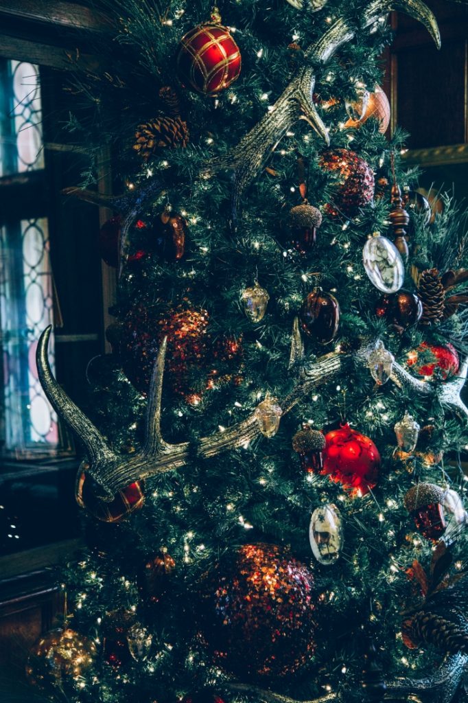 A closeup image of a Nutcracker themed Christmas tree with lights, ornaments, and reindeer antlers.