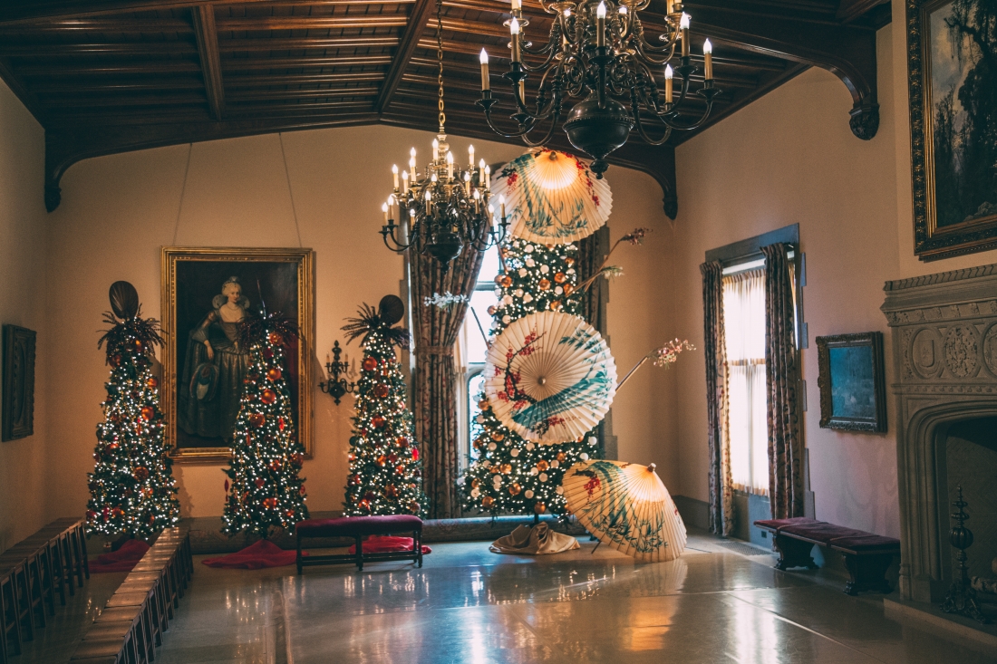 Another scene from the ice skating room at Paine Art Center's Nutcracker in the Castle display. Paper umbrellas hanging from the ceiling next to brightly-list Christmas trees.