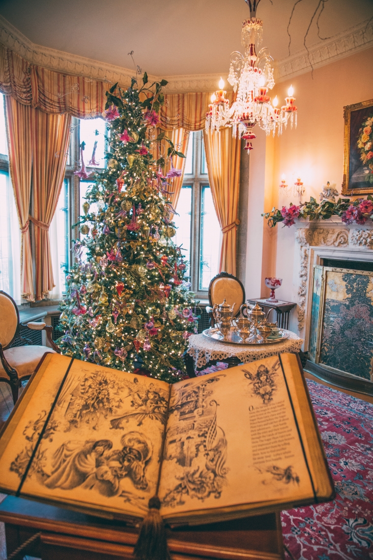 Another scene from The Nutcracker depicted in an elegant sitting room with a themed Christmas tree decorated with colorful ornaments and lights. The Nutcracker storybook is open on a pedestal in the forefront of the image.