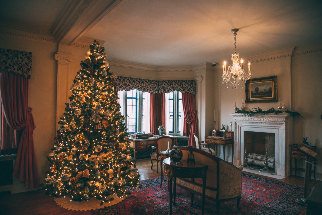 An elegant room with a fireplace and large Christmas tree, decorated with lights and ornaments, inside The Paine Art Center's Nutcracker in the Castle event.