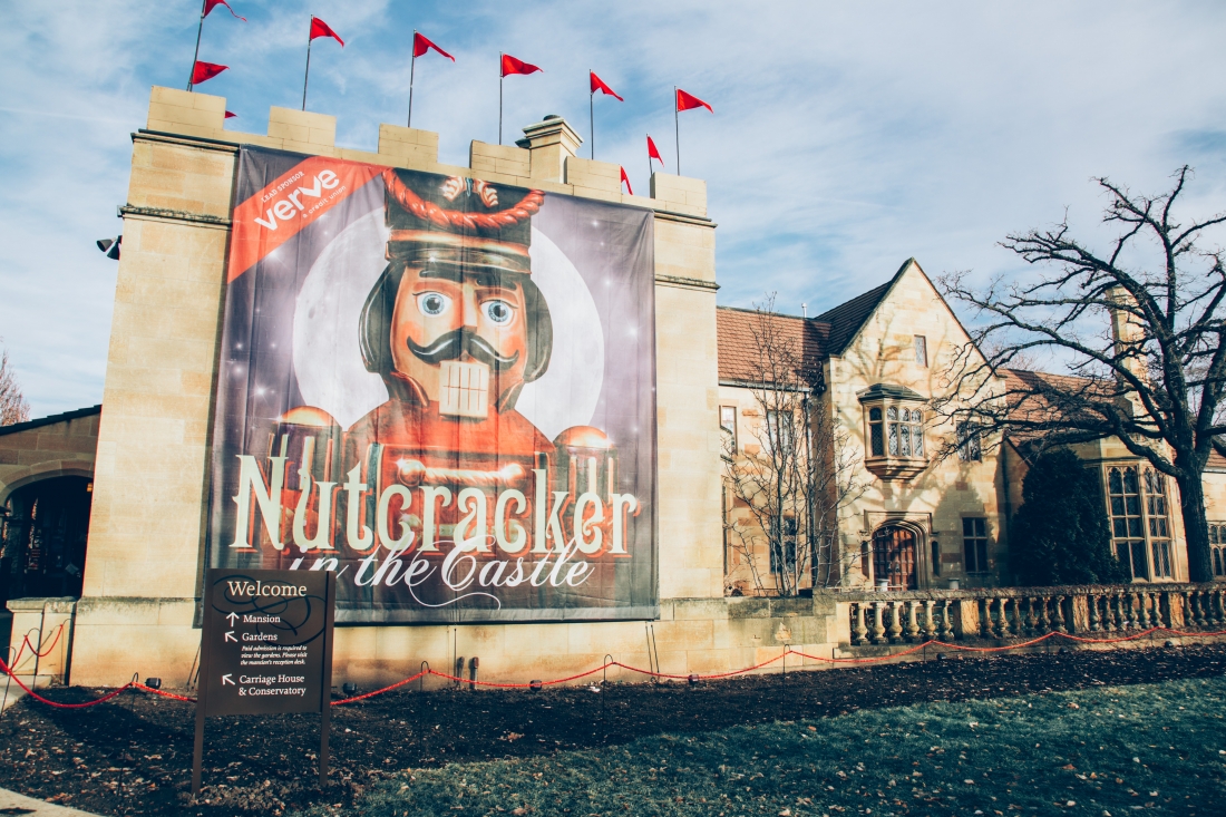 A large banner hangs on a brick wall, advertising the Nutcracker in the Castle event at the Paine Art Center in Oshkosh, Wisconsin.