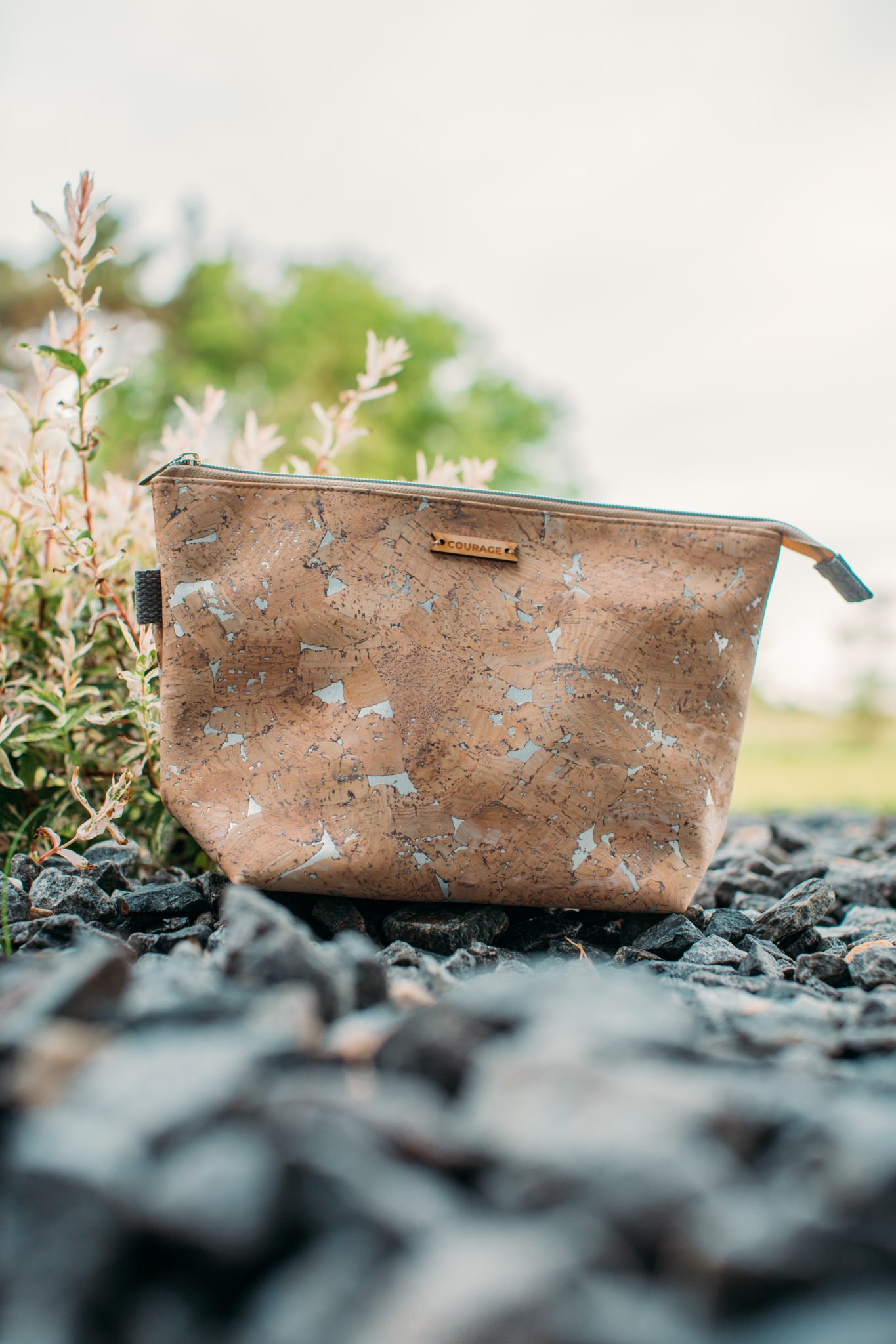 A closeup image of the Carry Courage cosmetic bag -- a sustainable travel bag made from cork material, with a top zipper and a brand label on the side.