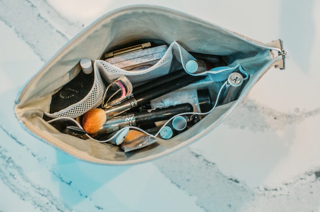 An overhead image of the ADVENTURER cosmetics bag from Carry Courage, showing all the contents inside. The bag is lined with mesh pockets for holding cosmetics and makeup tools.