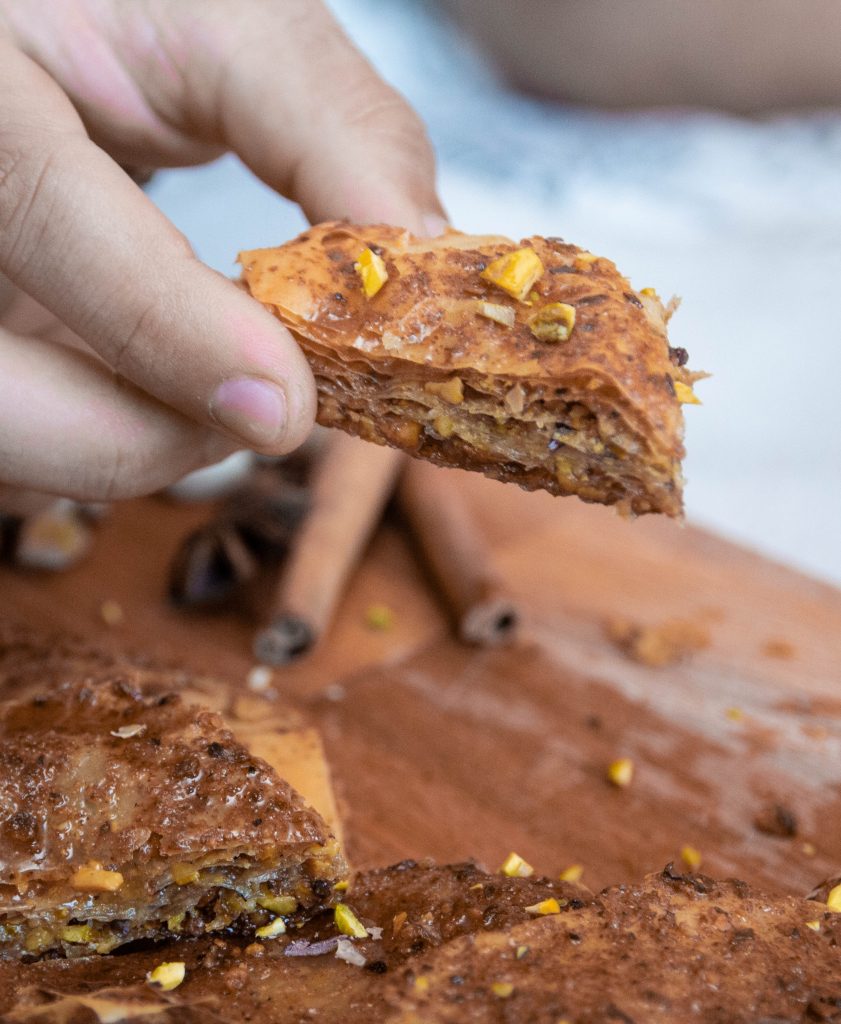 A person holding a piece of baklava