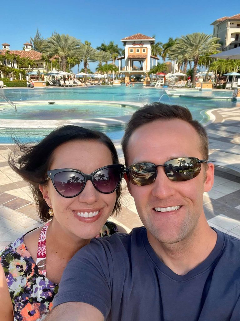 A man and woman taking a selfie in front of a pool.