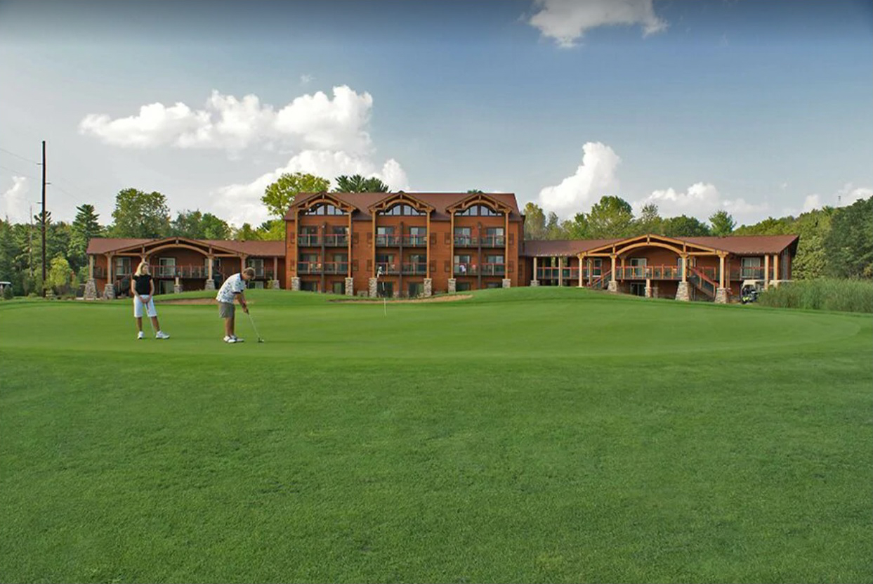 An exterior image of the Coldwater Canyon golf course and Chula Vista resort in the Wisconsin Dells. A man and a woman stand on the putting green in the front of the image.