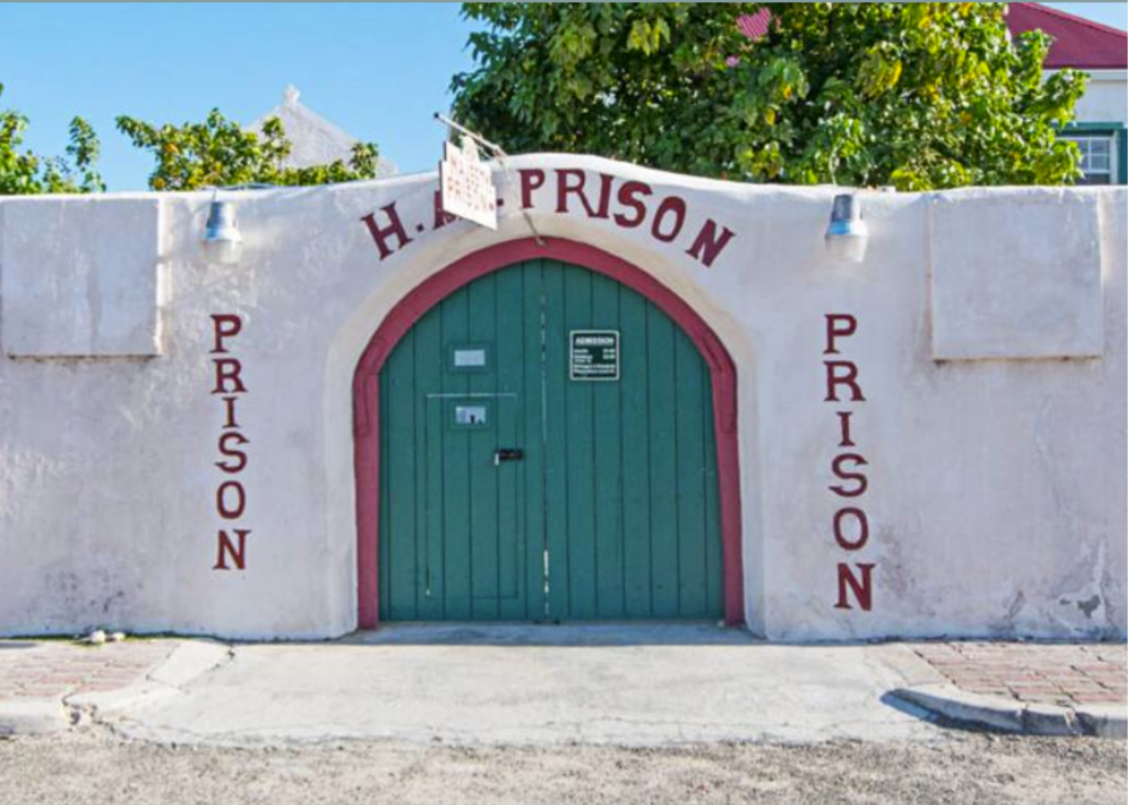 A building with a green door and a sign that says H.M. prison. 