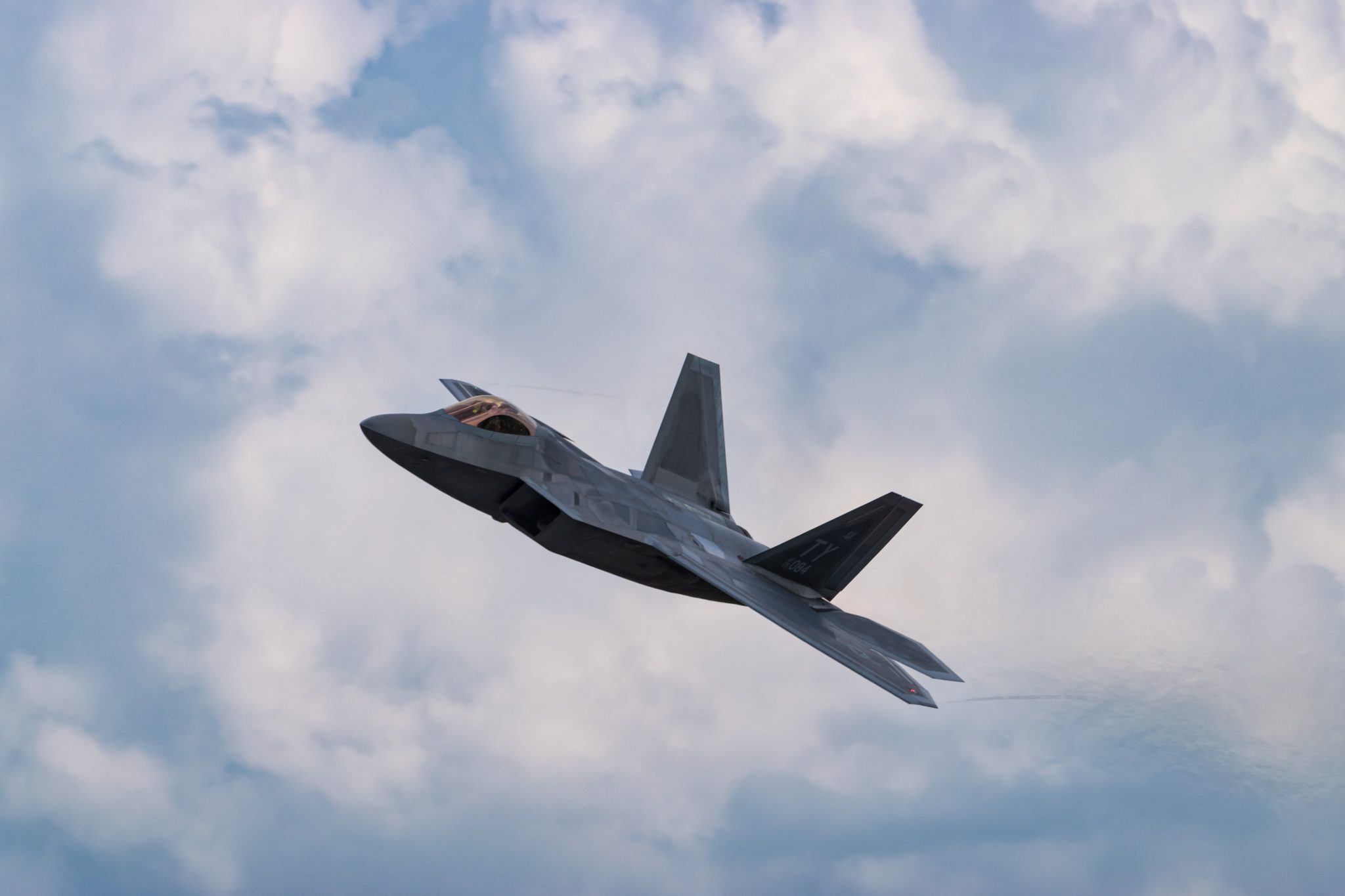 An old fighter jet flies across a cloudy blue sky during the EAA Airventure air show in Oshkosh, Wisconsin.