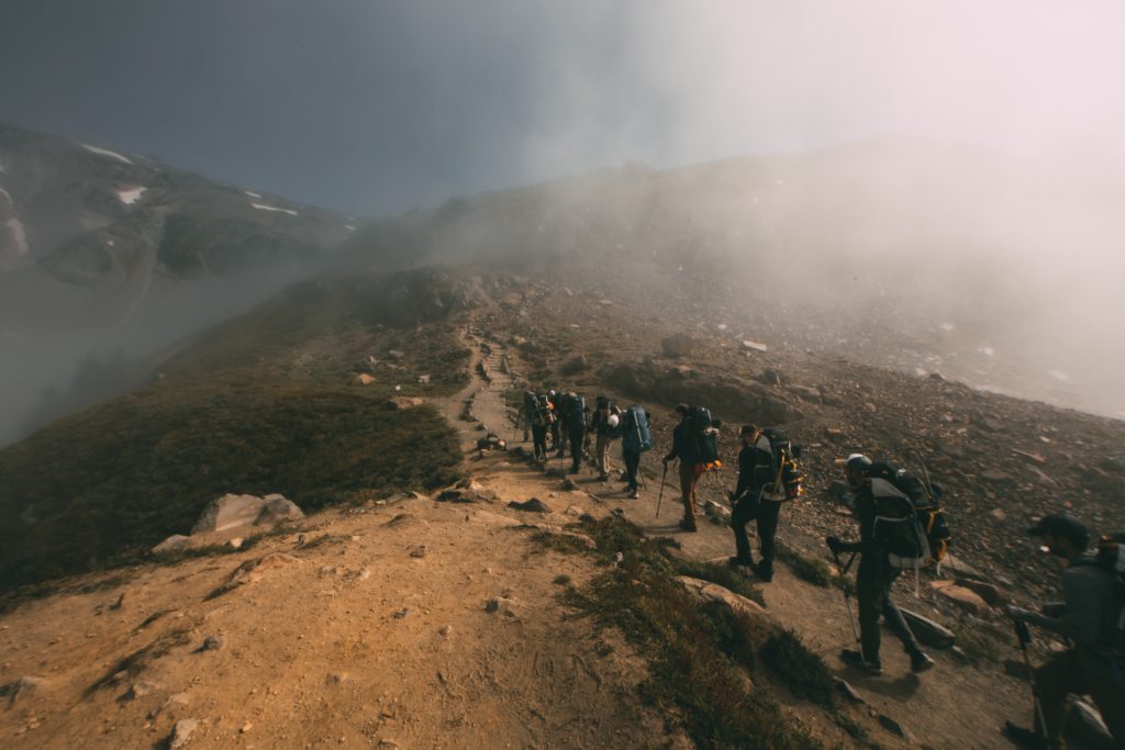 the Skyline Trail in Paradise featuring a line of hikers ascending a steep incline through a cloud