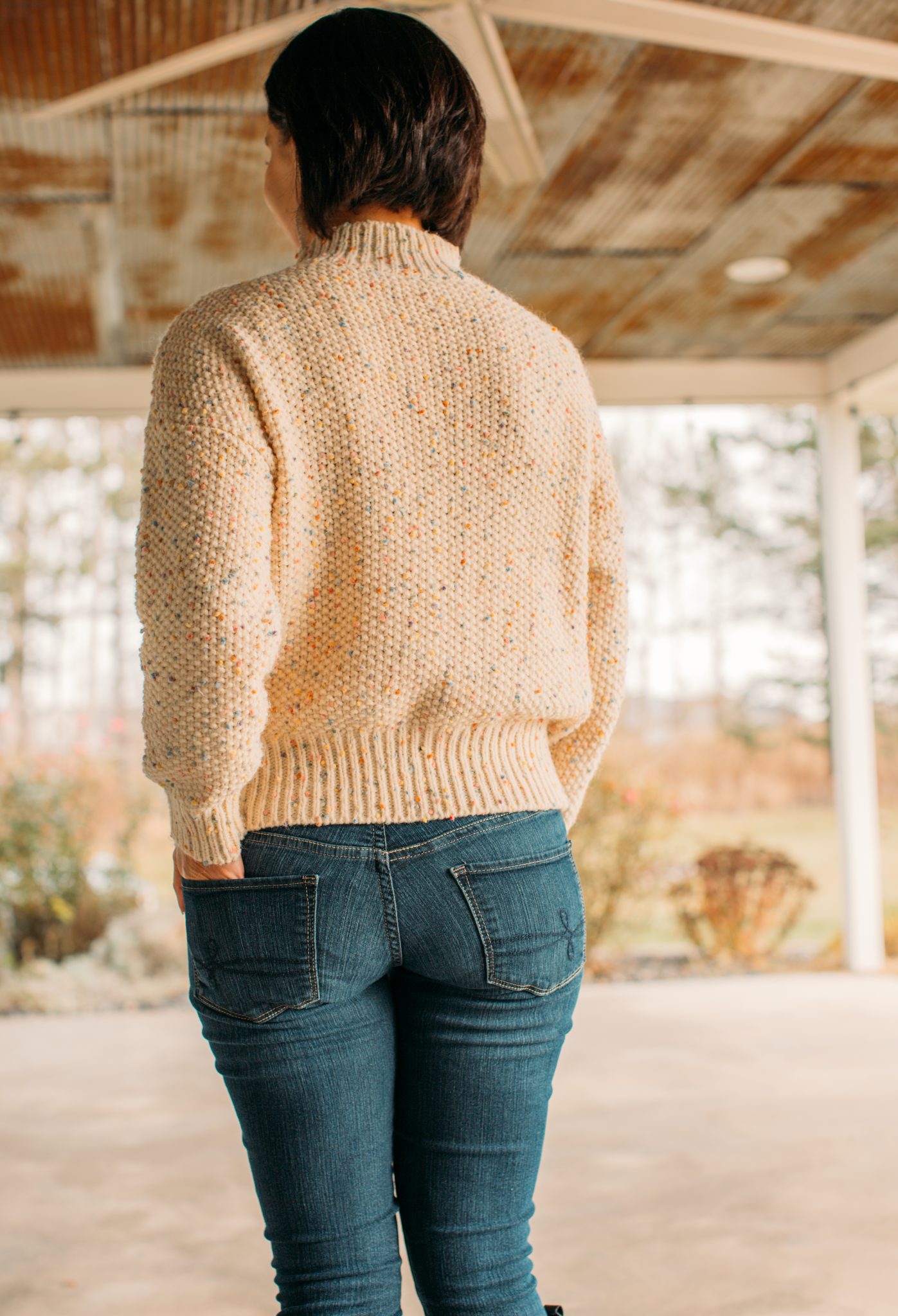 A woman wearing a colorful dots high neck chunky knit sweater from Chicwish.