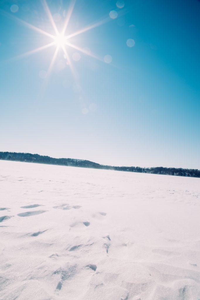 A frozen and snow-covered Elkhart Lake on a clear, cloudless, sunny day with blue skies.