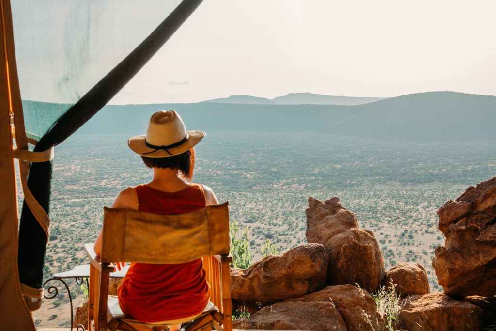 A woman sits in a chair in a tent overlooking a mountain.