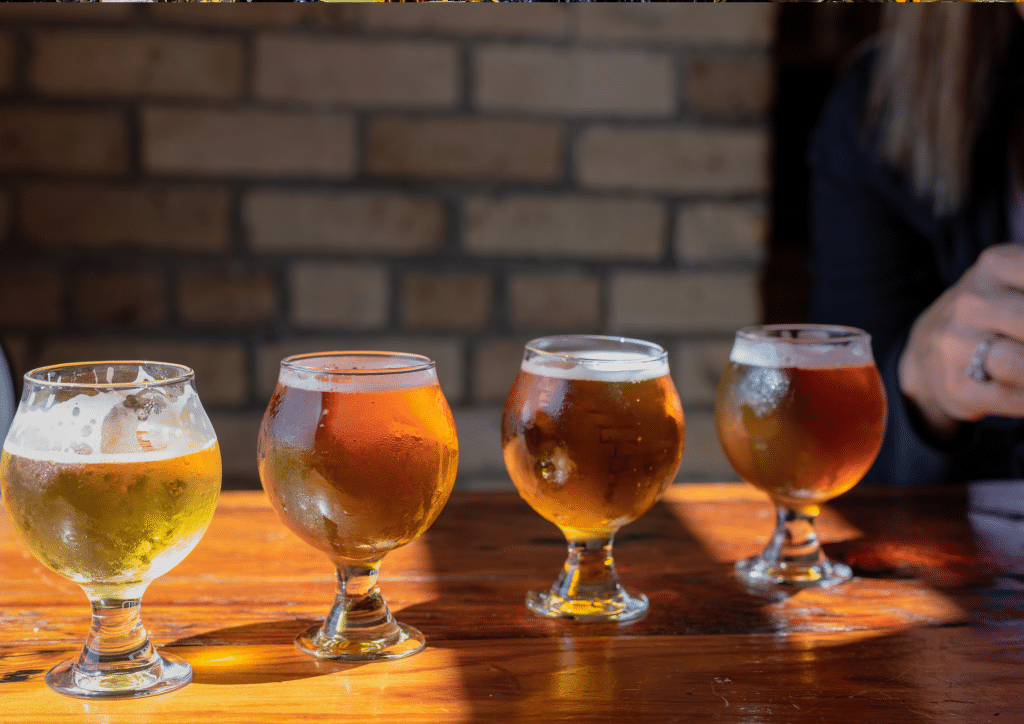 A row of beer glasses on a wooden table.