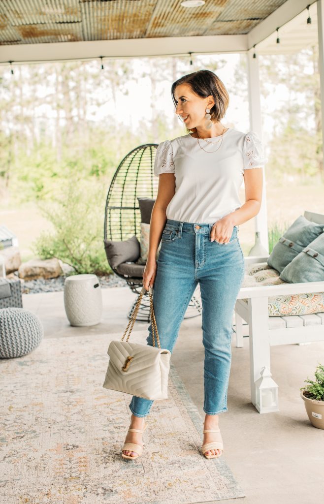 Lindsey wearing a white blouse with cropped jeans, nude colored Cult Gaia sandals and holding a YSL loulou medium bag