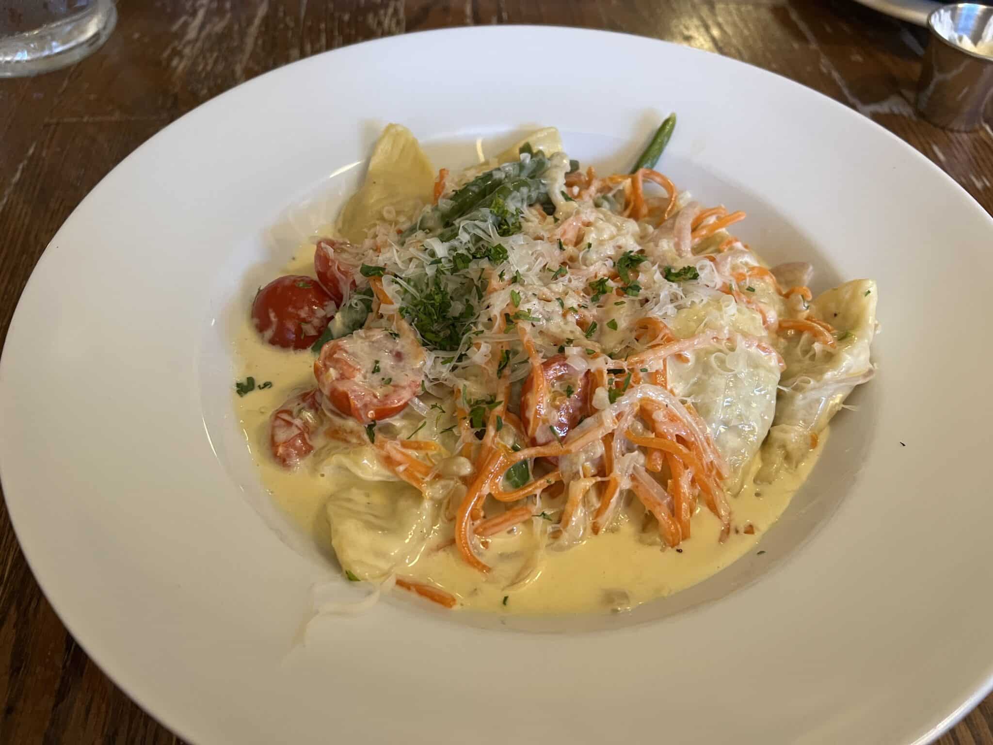 A creamy pasta dish is topped with cheese and served in a round pasta bowl. 