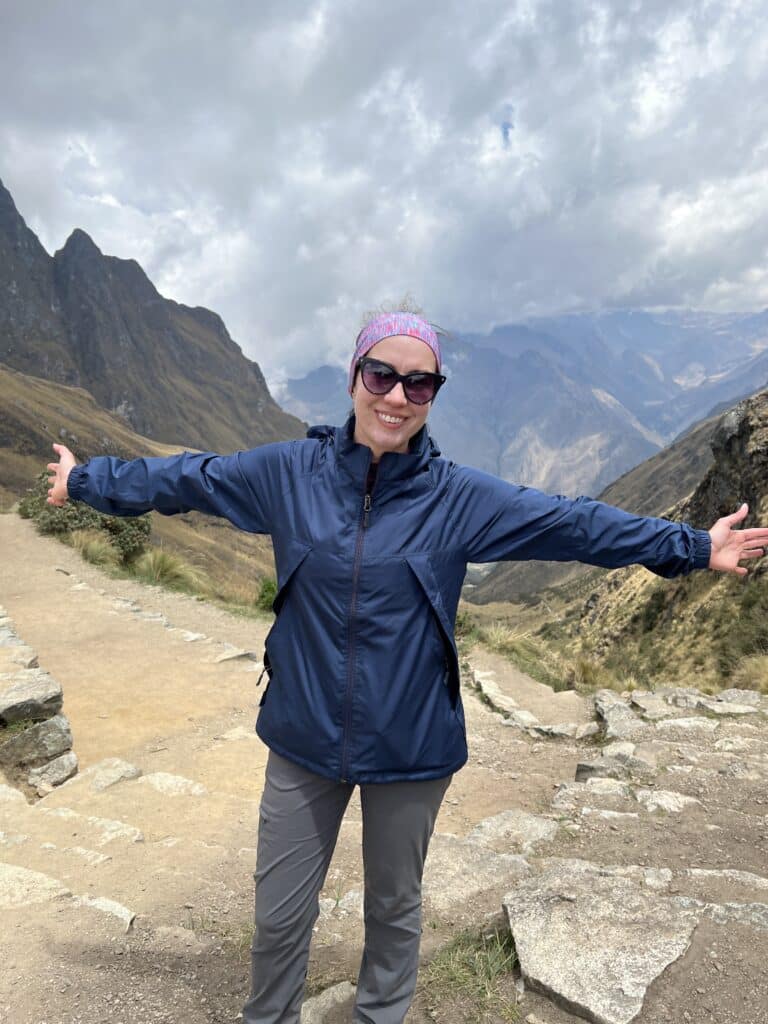 A woman with her arms outstretched in front of a mountain.