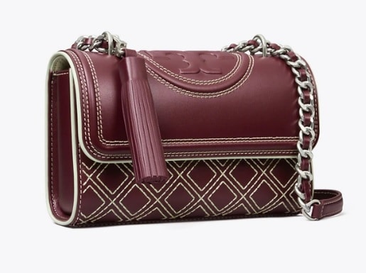 This Tory Burch shoulder bag is crafted from a Mulberry wine colored leather with an embroidered diamond pattern on the body of the bag. The Tory Burch logo is embossed on the top of the bag, next to a silver chain.