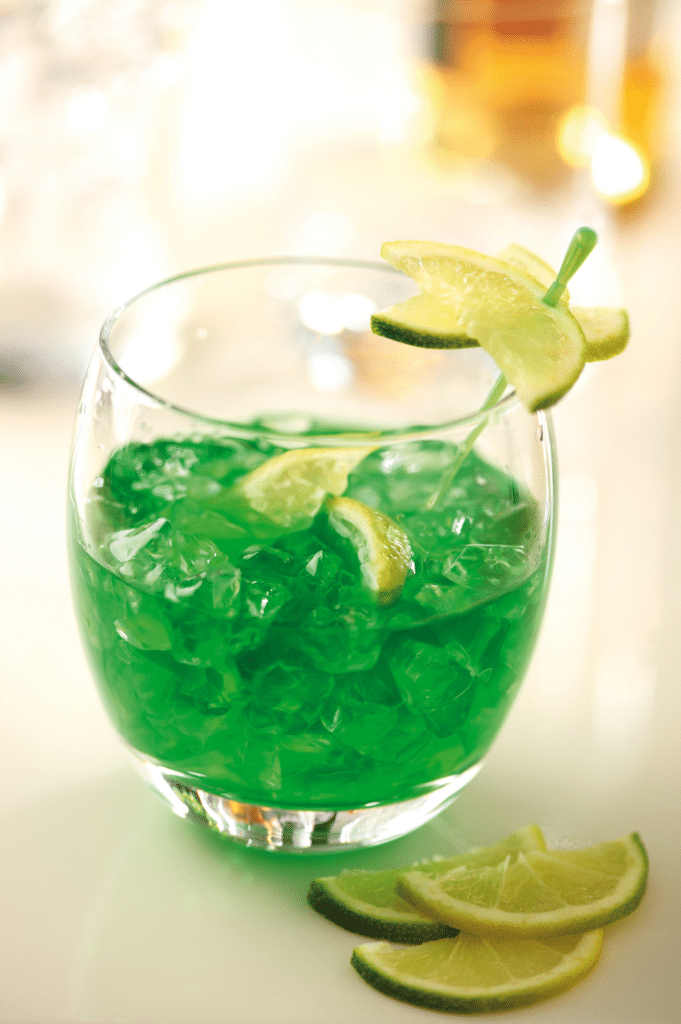 A glass with a green drink in it.