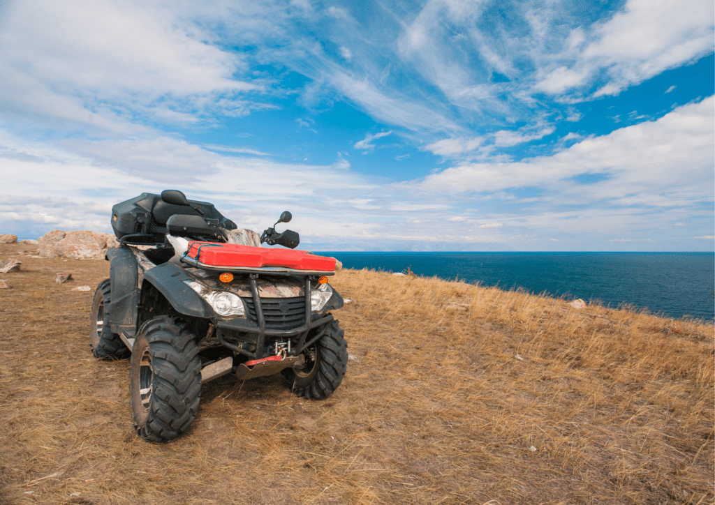 An ATV sits on the side of a cliff overlooking the ocean.