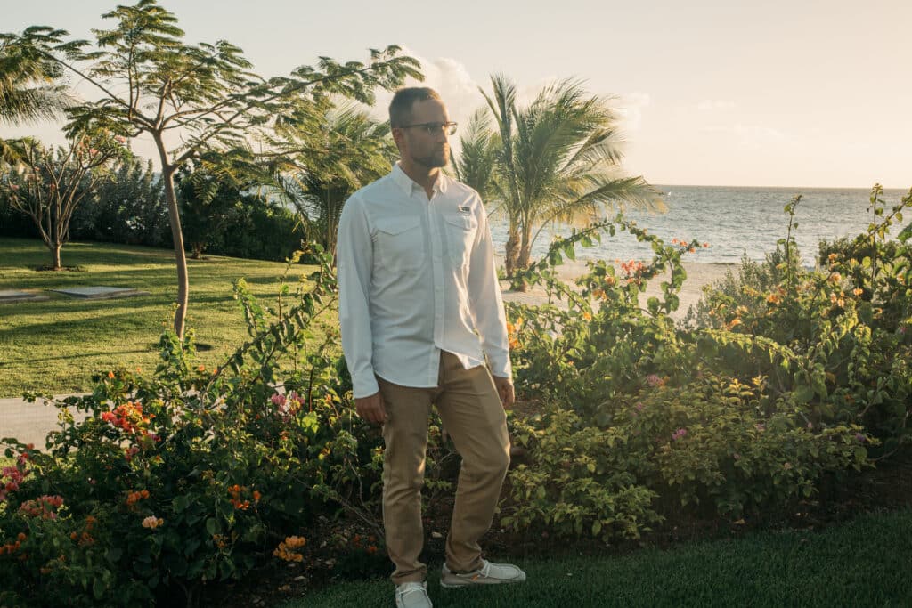 A man in a white shirt standing in front of a flower garden.