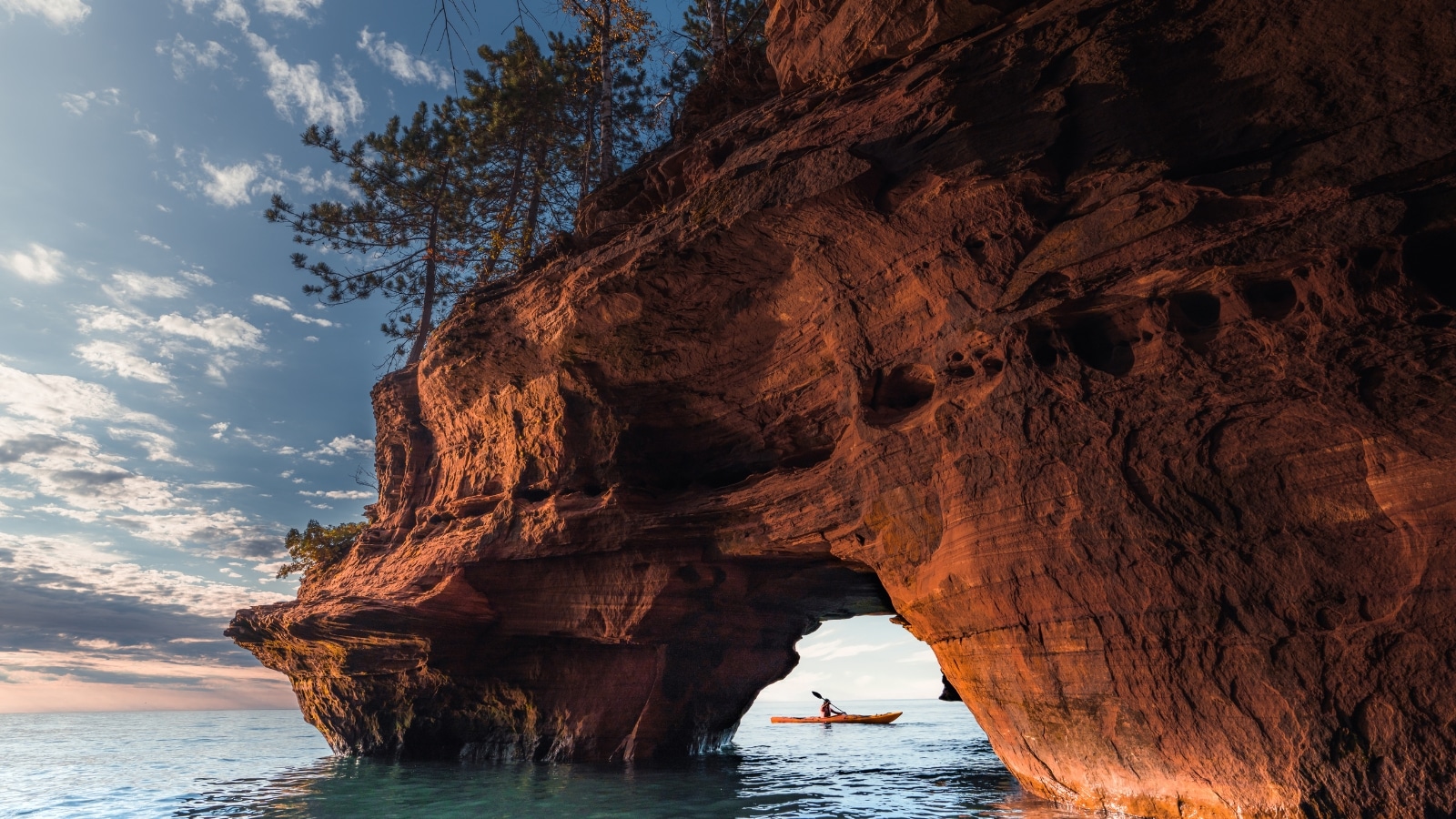 A stunning rock formation towers over the calm waters of Lake Superior at Apostle Islands in Bayfield Wisconsin