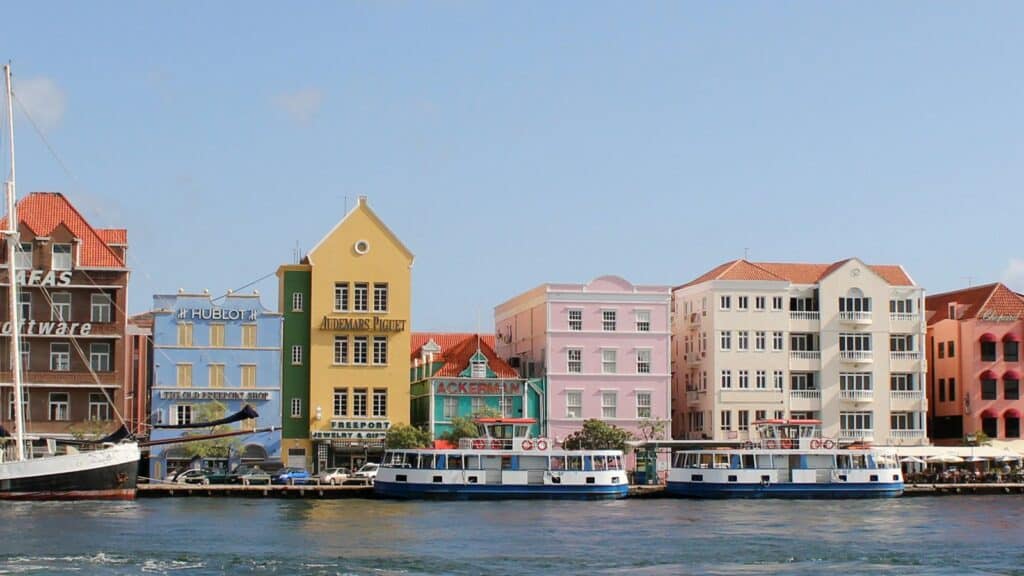 Colorful buildings on the water next to a boat in Curacao.