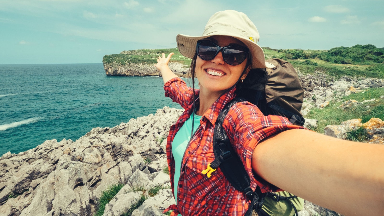 Happy woman backpacker traveler take a selfie photo on amazing ocean coast