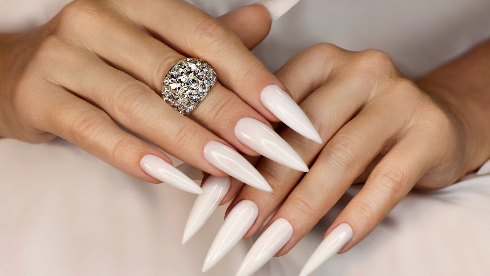 Long light manicure with jewelry on a woman's hand.