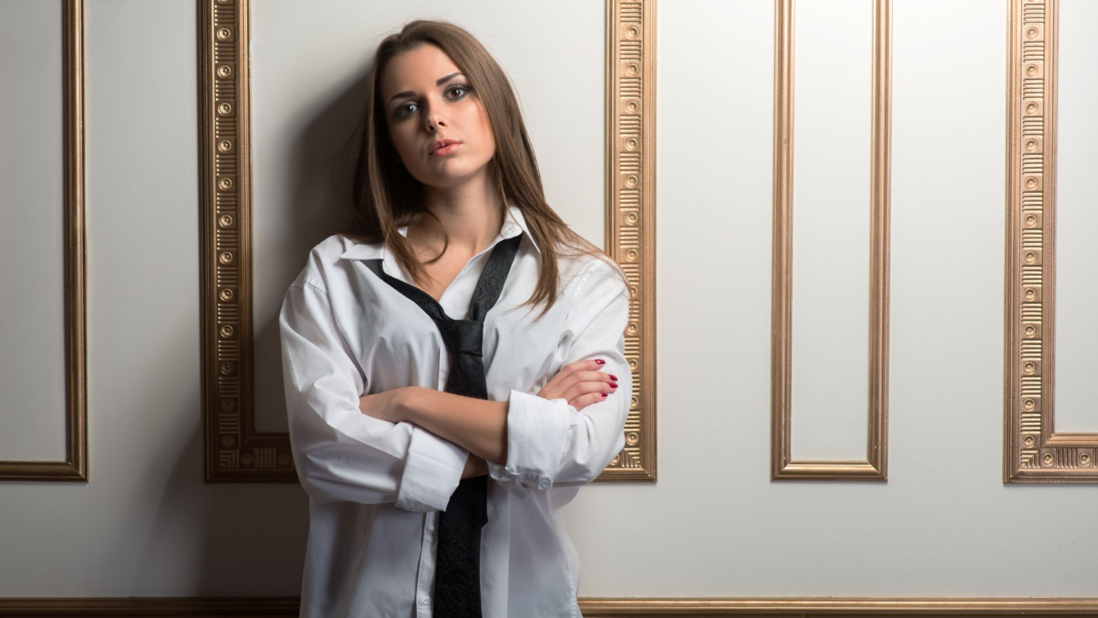 Full length portrait of young sexy woman wearing men suit oversize and tie holding jacket behind her back, provocative look, interior shot