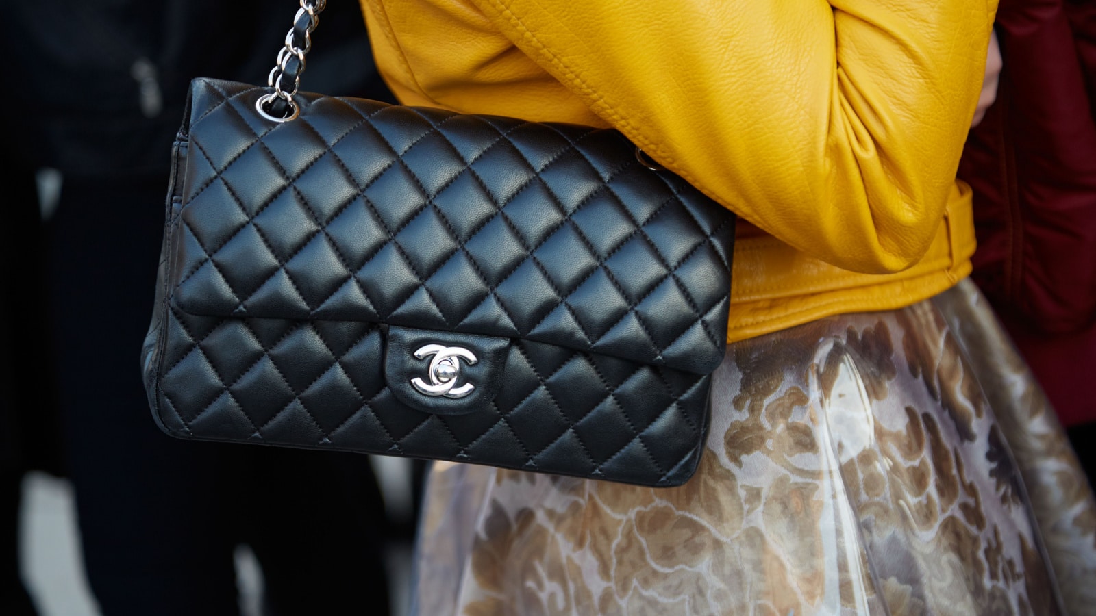 MILAN - FEBRUARY 25: Woman poses with black leather Chanel bag and yellow jacket before Cristiano Burani fashion show, Milan Fashion Week Day 2 street style on February 25, 2016 in Milan.