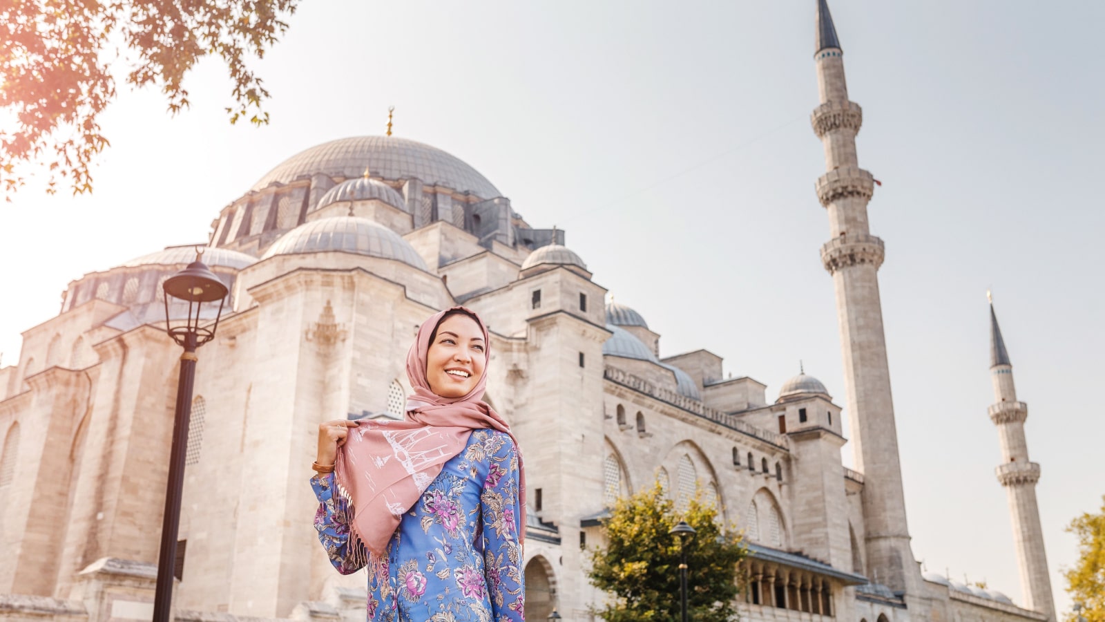 Happy attractive muslim woman in Istanbul, Turkey, posing in courtyard of Suleymaniye mosque, religion and travel concept.