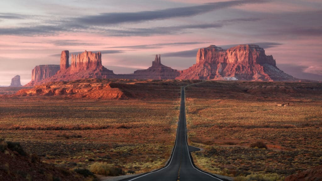 Forrest Gump Point, red rock at Monument Valley, Navajo Tribal Park, Arizona USA. Stunning view and scenic road in Utah during sunrise. Depth of long empty road.