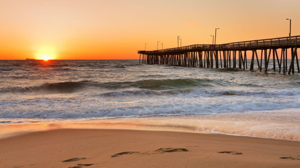 Fishing Pier at Sunrise at Virginia Beach, Virginia, USA. Virginia Beach, a coastal city in southeastern Virginia, lies where the Chesapeake Bay meets the Atlantic Ocean.